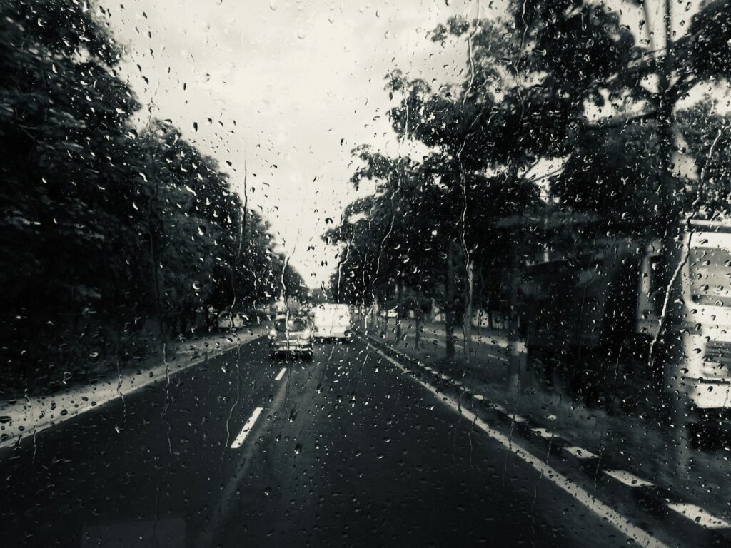 vue d'une route mouillée par la pluie à travers un pare-brise de voiture