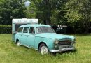 Charming vintage Peugeot and caravan parked in a lush, summer landscape in Saint-Lary-Soulan, France.