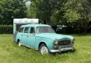 Charming vintage Peugeot and caravan parked in a lush, summer landscape in Saint-Lary-Soulan, France.