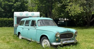 Charming vintage Peugeot and caravan parked in a lush, summer landscape in Saint-Lary-Soulan, France.