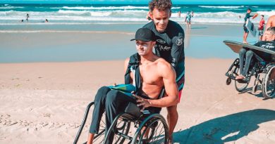 man in black shorts sitting on black wheelchair on beach during daytime