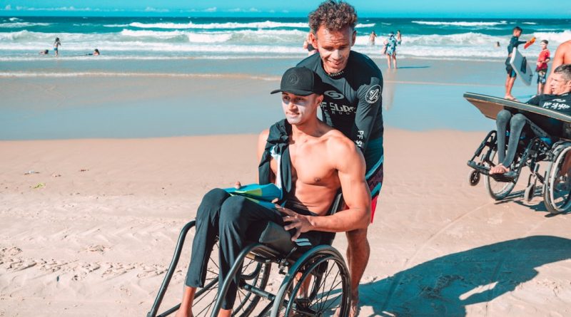 man in black shorts sitting on black wheelchair on beach during daytime