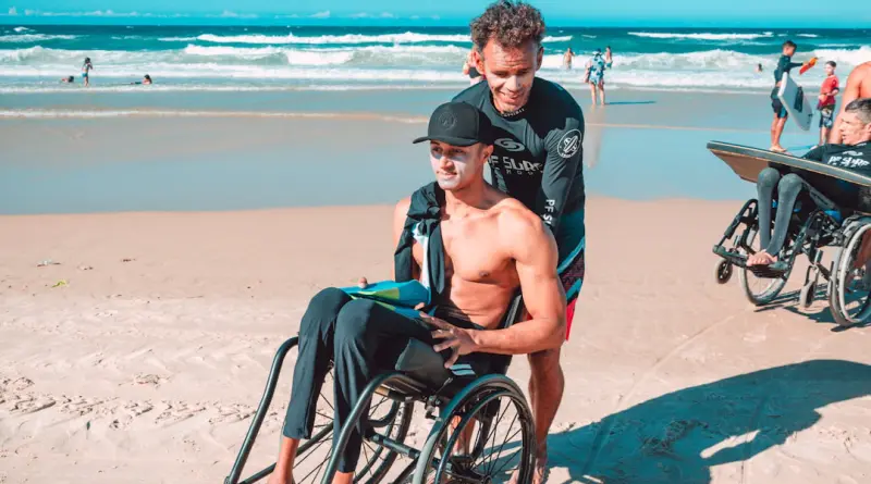 man in black shorts sitting on black wheelchair on beach during daytime
